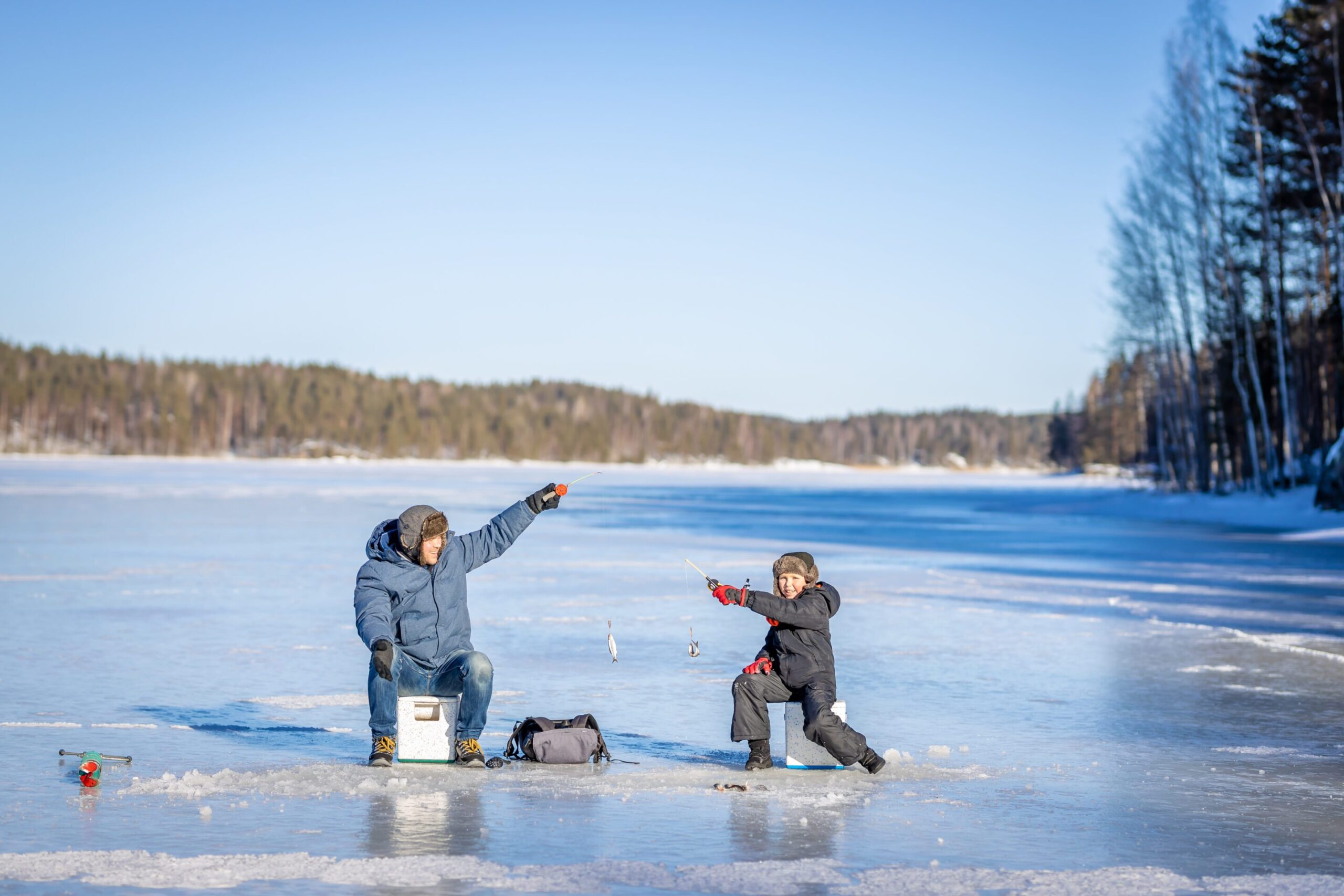 Father and son at winter fishing on frozen lake